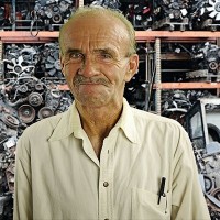 Buck Buchanan Man with a salt-and-pepper mustache and thinning hair, standing in front of an array of auto parts